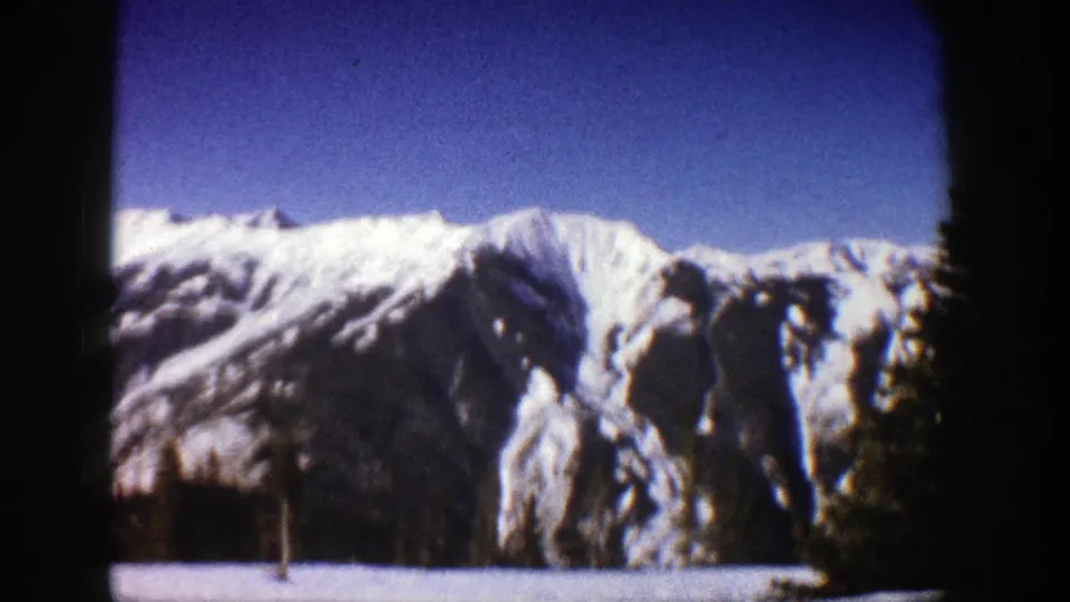1961 Aspen, Colorado view of a snowy mountain face with blue sky, tree shadows, and visible 8mm frame edges.