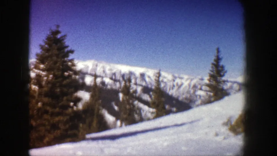 Late-frame 1961 Aspen, Colorado view of evergreens on a snowy slope beneath a bright mountain skyline.