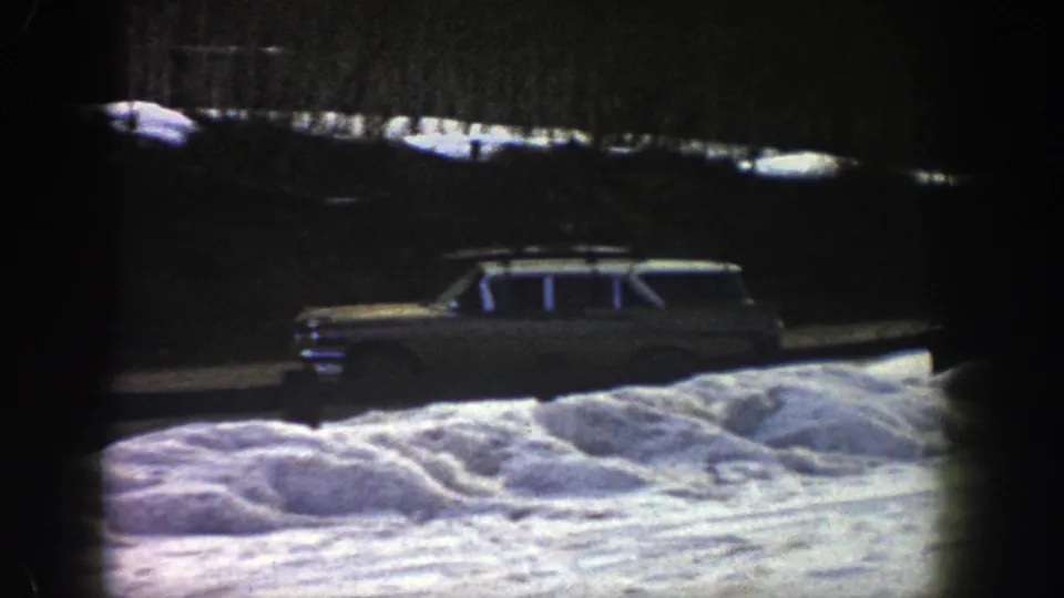 A mid-century station wagon appears beside piled snow in the Aspen winter road scene, with dark trees and exposed film edges.