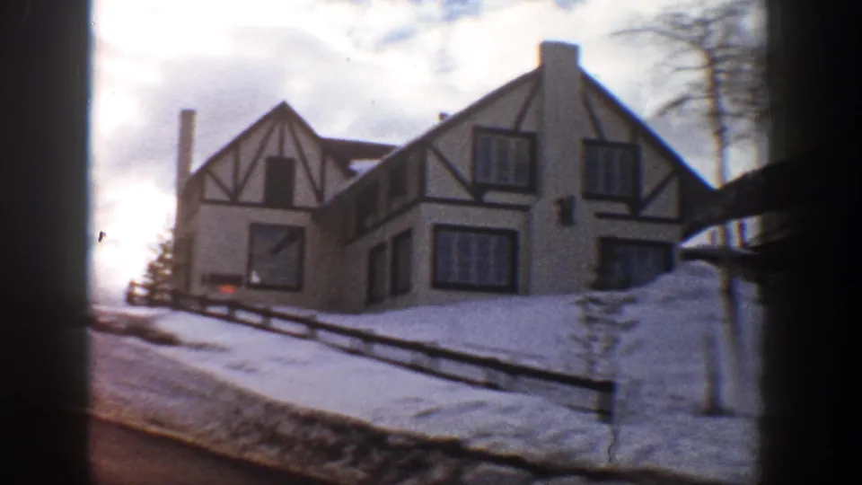 Aspen, Colorado lodge facade from 1961 home-movie footage, with timber trim, snowbanks, bare trees, and a winter roadway.