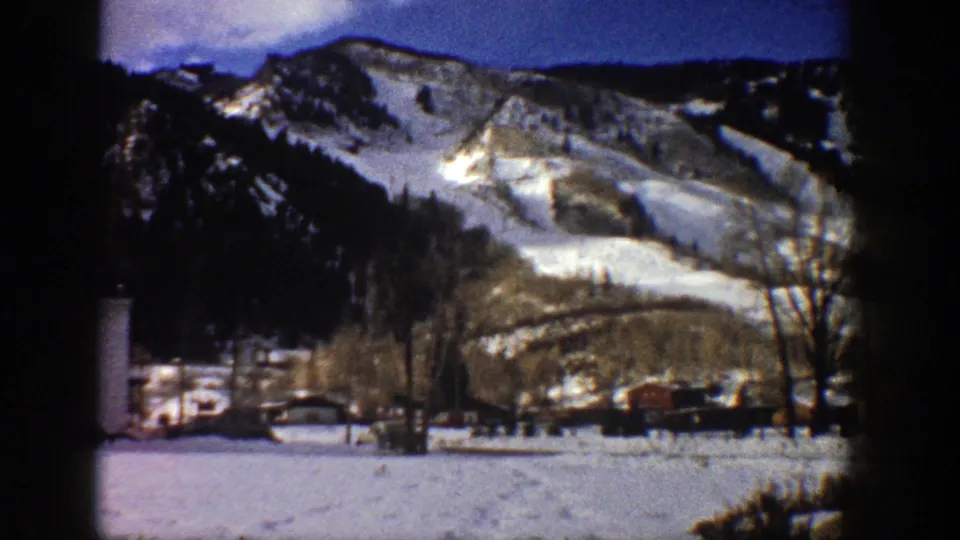 1961 Aspen, Colorado winter view with snow-covered slopes, bare trees, and low buildings in the valley.