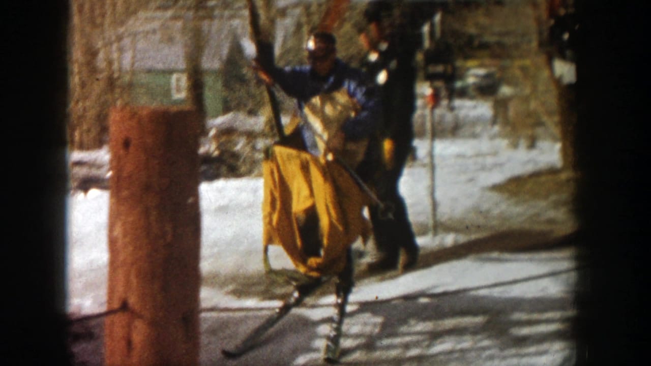 Worker guiding a yellow lift carrier near a pole and snowy resort ground.