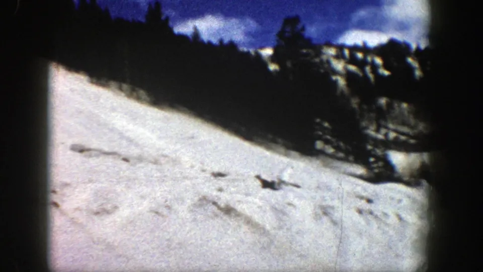 Aspen, Colorado winter slope on 8mm film, with dark evergreens and rocky snow edges visible at frame right.