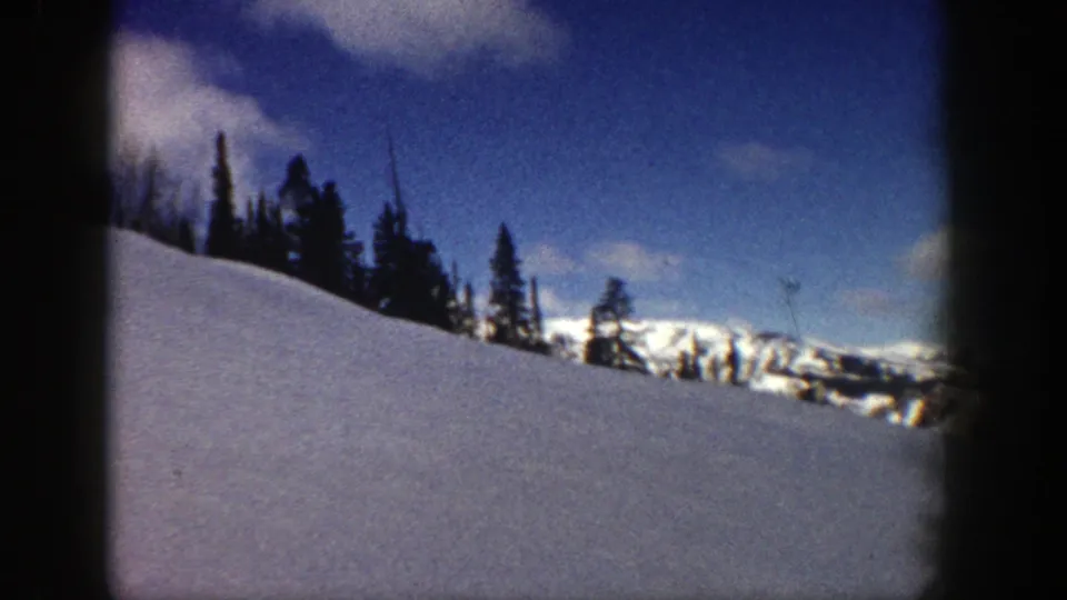 1961 Aspen winter view with a snow-covered foreground, evergreen ridge, and distant mountain peaks in soft home-movie focus.