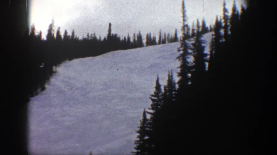 Aspen, Colorado 1961 frame with a snowfield rising toward a treeline, bordered by dark conifers and 8mm gate edges.