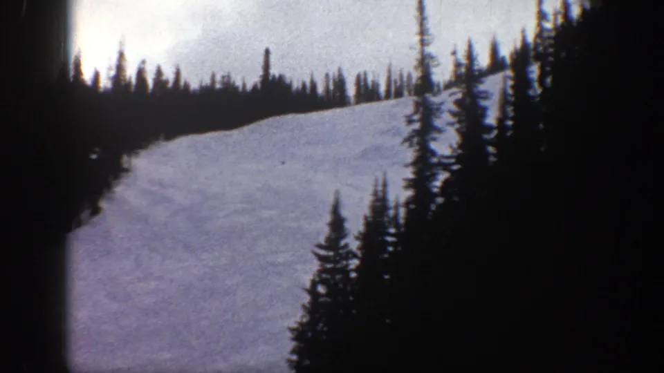 1961 Aspen 8mm frame showing a snow-covered hillside, dark conifers, and soft color from handheld home-movie footage.