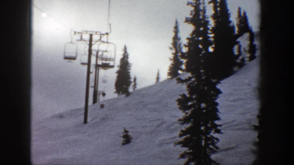 Aspen, Colorado ski lift crosses a snow-covered mountainside in a grainy 1961 8mm frame.