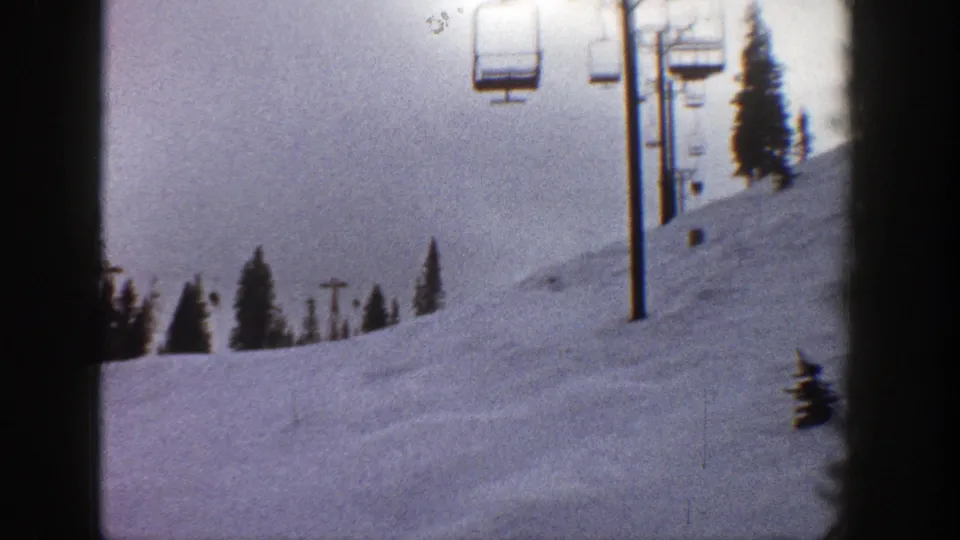1961 Aspen winter frame showing chairlift equipment on a quiet snowy mountainside with evergreens.