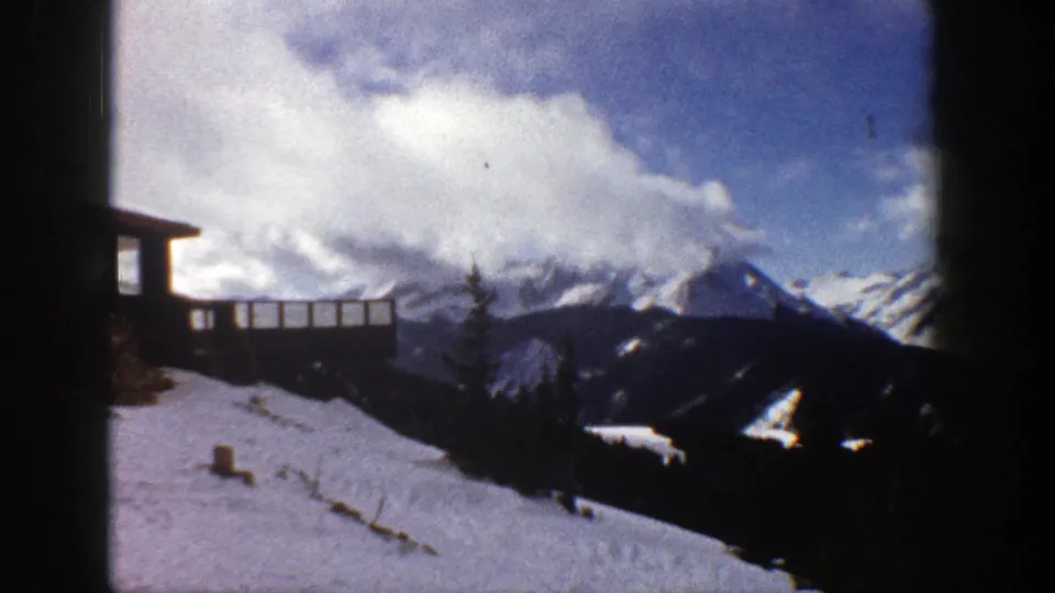 1961 Aspen, Colorado view of a snowy overlook or ridge with timber railing, dark trees, and distant alpine peaks.