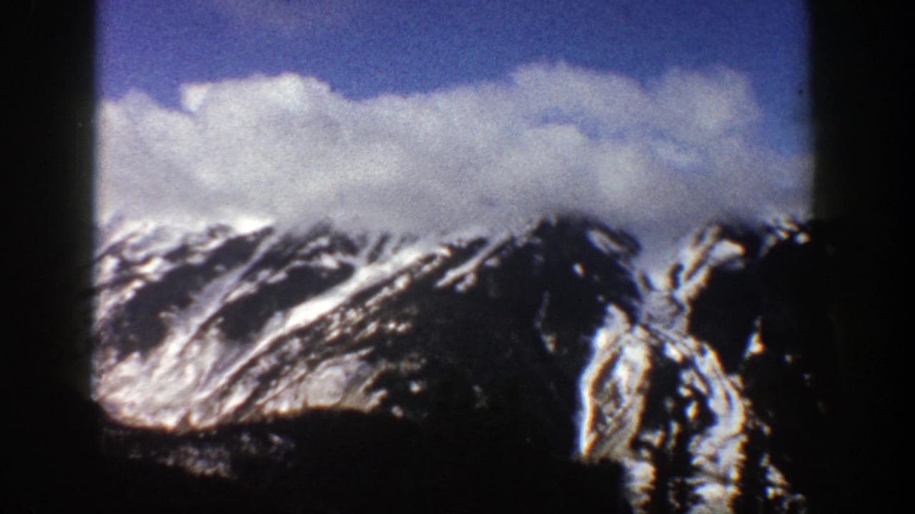 Snowy mountain range with a large cloud bank and dark vertical film border.