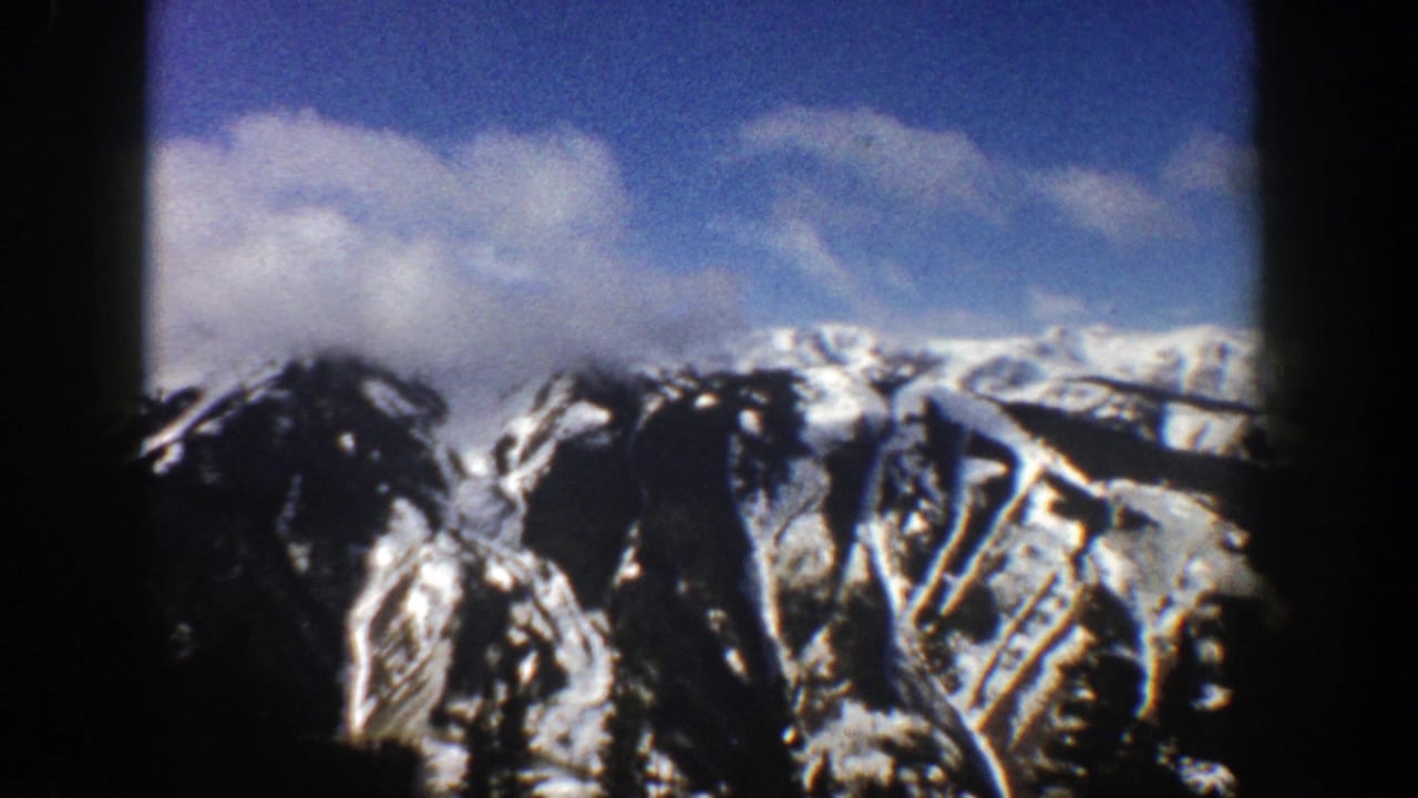 Distant snowy mountain range under clouds with dark vertical frame borders.