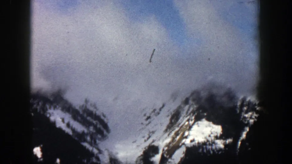 1961 Aspen, Colorado 8mm view of alpine peaks with snow patches, low cloud, and visible rounded film-frame edges.