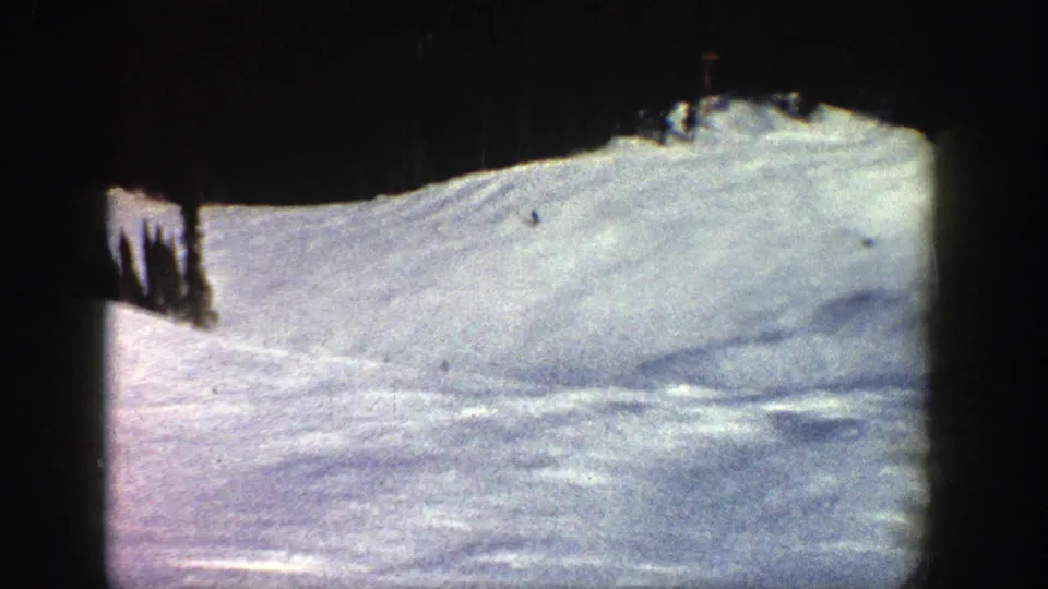 Distant skiers appear on a bright Aspen slope in a 1961 8mm home-movie frame with visible dark film borders.