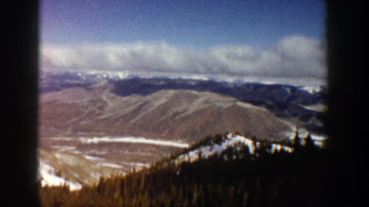 Distant ridges and a snowy valley seen past dark film edges.