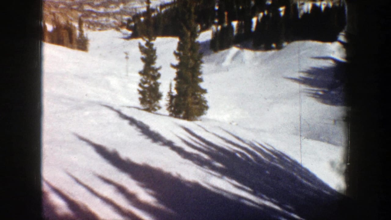 Snowy mountain slope with evergreen trees, long shadows, and dark 8mm frame borders.