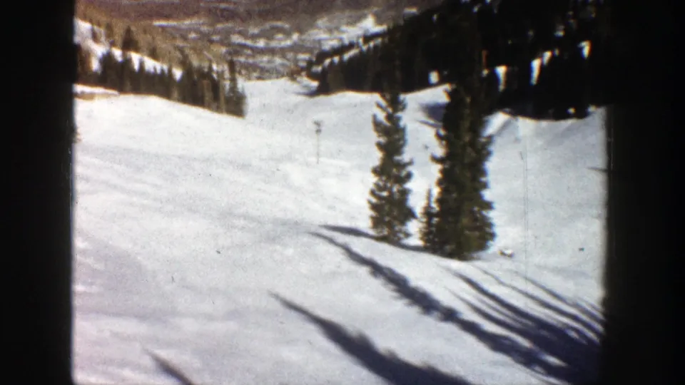 1961 Aspen 8mm still of a steep snow slope, clustered evergreens, and long shadow bands.