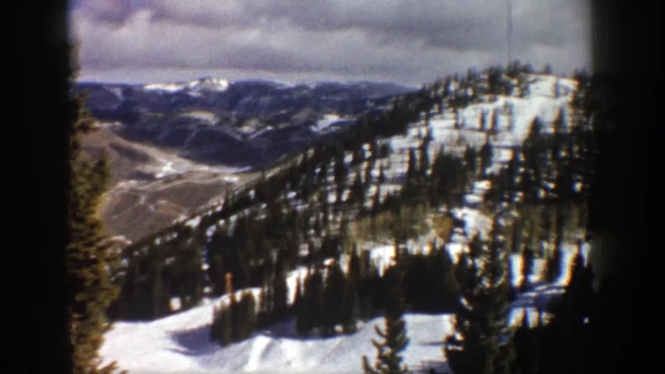 1961 Aspen, Colorado 8mm frame with a snowy pine-covered slope at right and a broad mountain valley stretching into the distance.