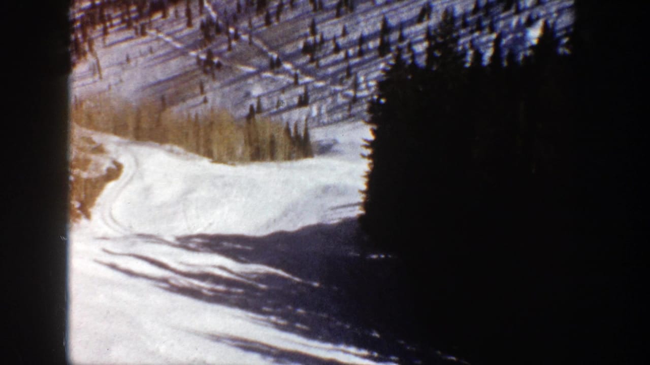 Aspen, Colorado 8mm frame with snow, curving tracks, dark evergreens, and pale trees in late-day light.