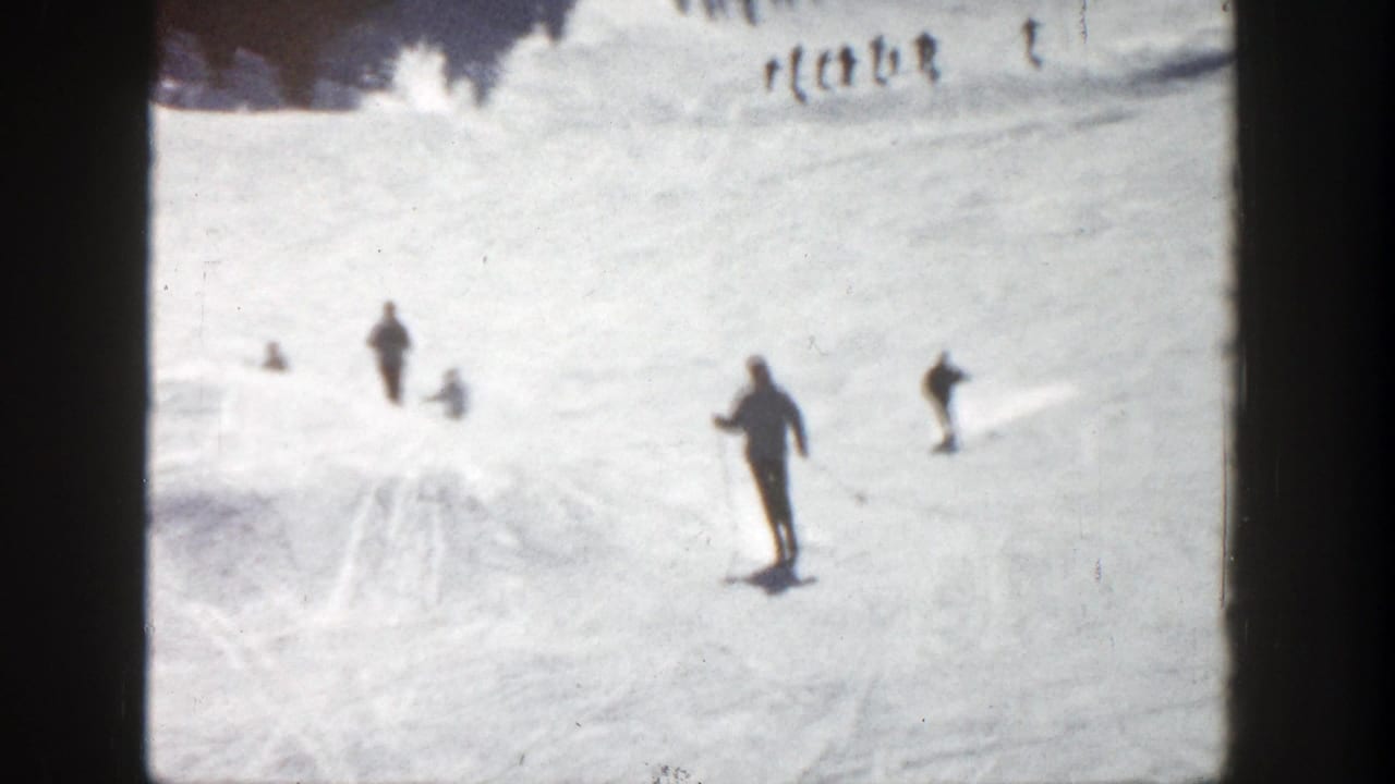 Several skiers descend a bright snowy slope with dark frame borders visible.