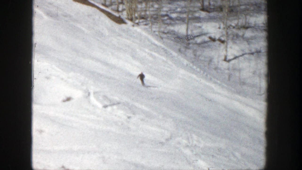 Skier in dark clothing turning on a snowy mountainside.