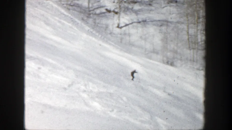 Near the end of the clip, the lone skier continues downhill across the open Aspen slope, with faint tracks and bare trees behind.