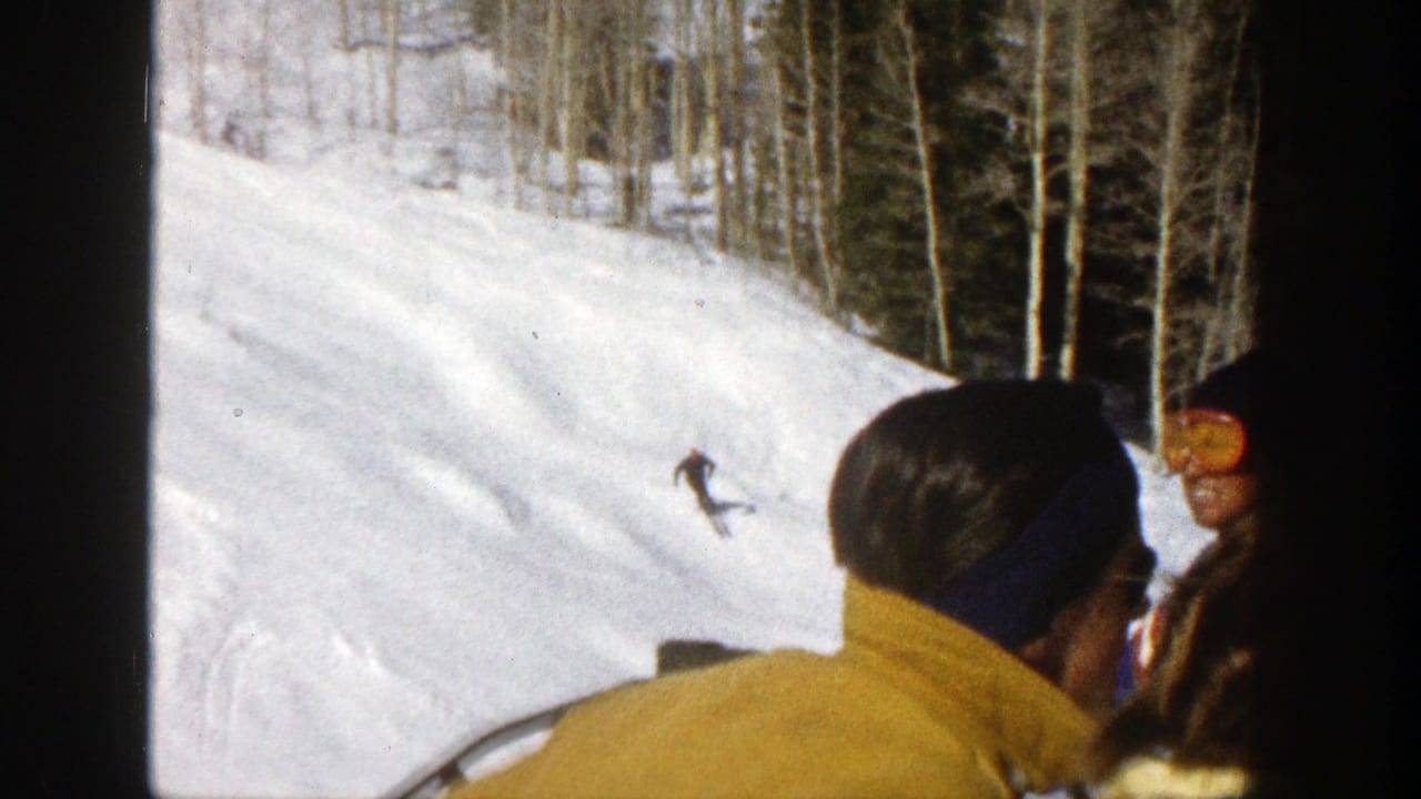 Lift riders watch a skier on a snowy slope beside bare trees.