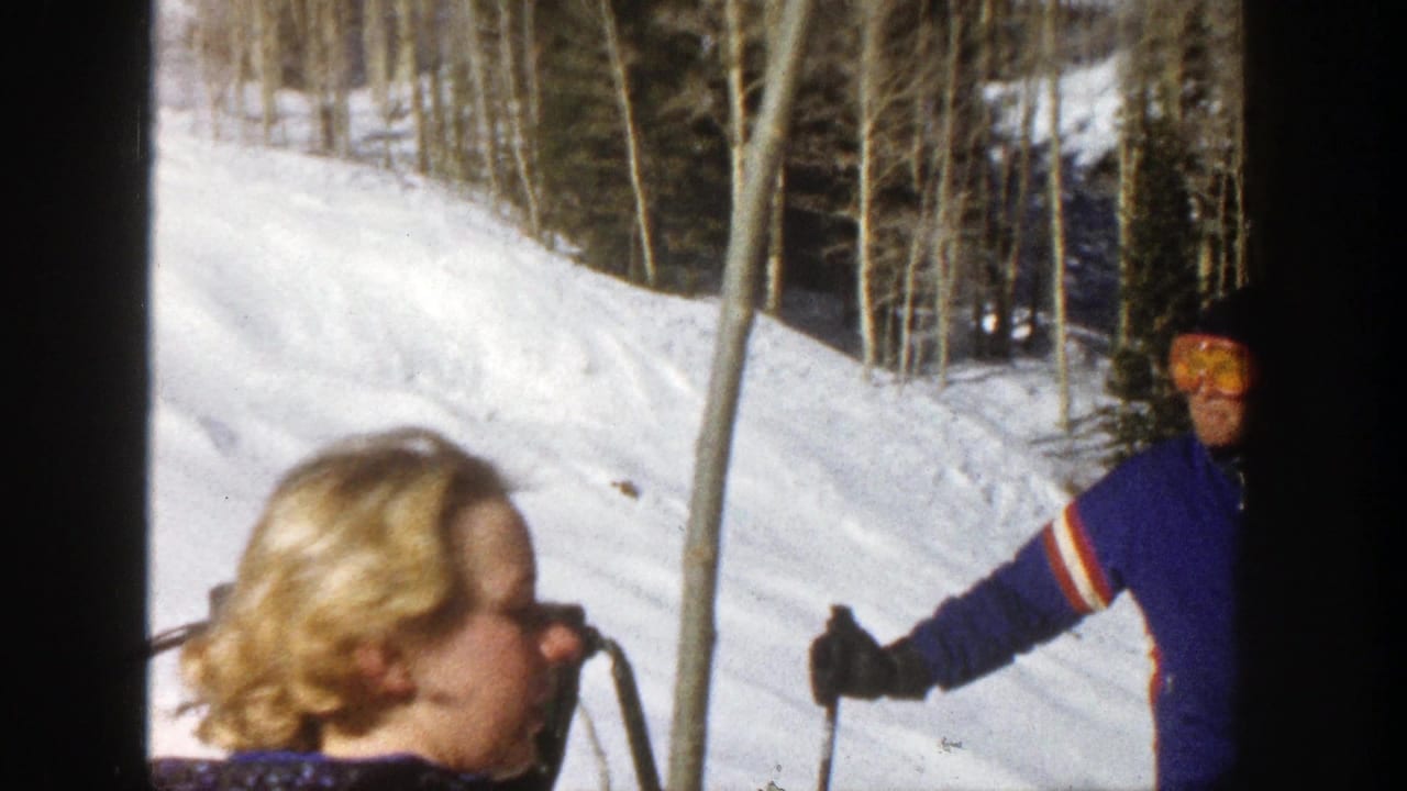 Skiers pause on a sunny snowy slope with aspen trees behind them.