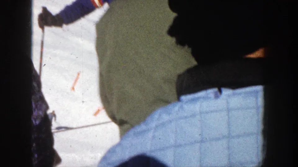 Home-movie frame from 1961 Aspen with skiers seen close to camera as others stand on the snowy slope beyond.