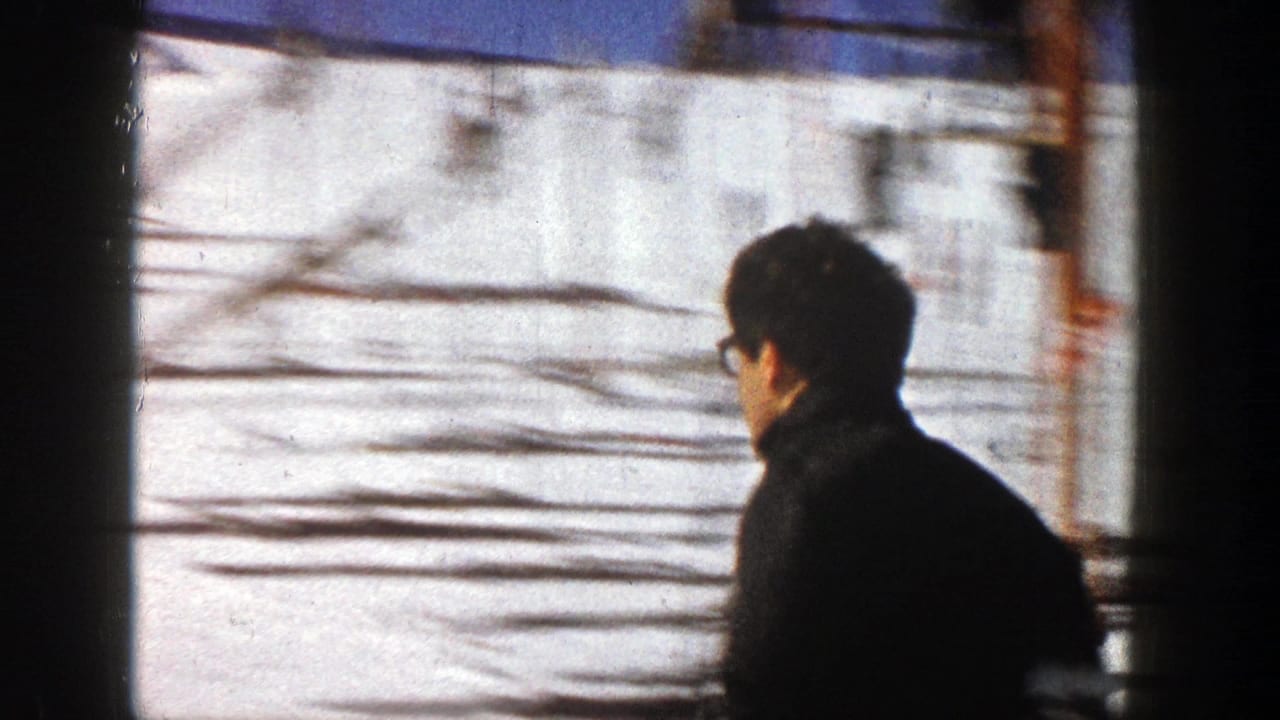 Dark-haired man in profile near a snowy ski slope with frame-edge shadowing.