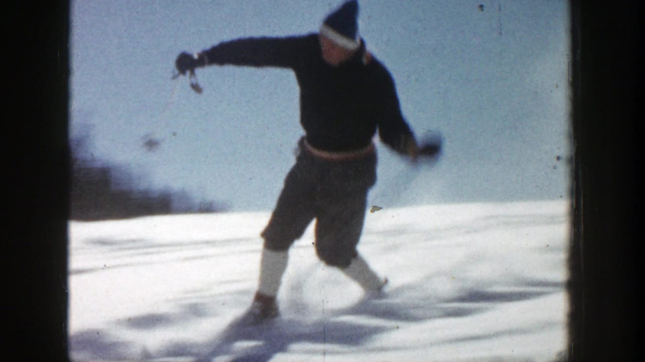 Skier leaning into motion with one arm extended on the snow.