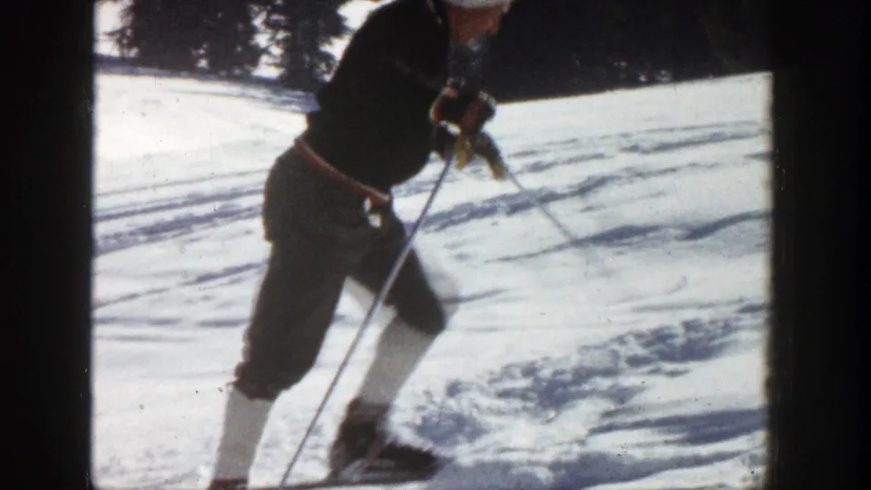 A closer 8mm frame shows the skier turning or slowing on the Aspen slope, with white lower-leg coverings and poles visible.