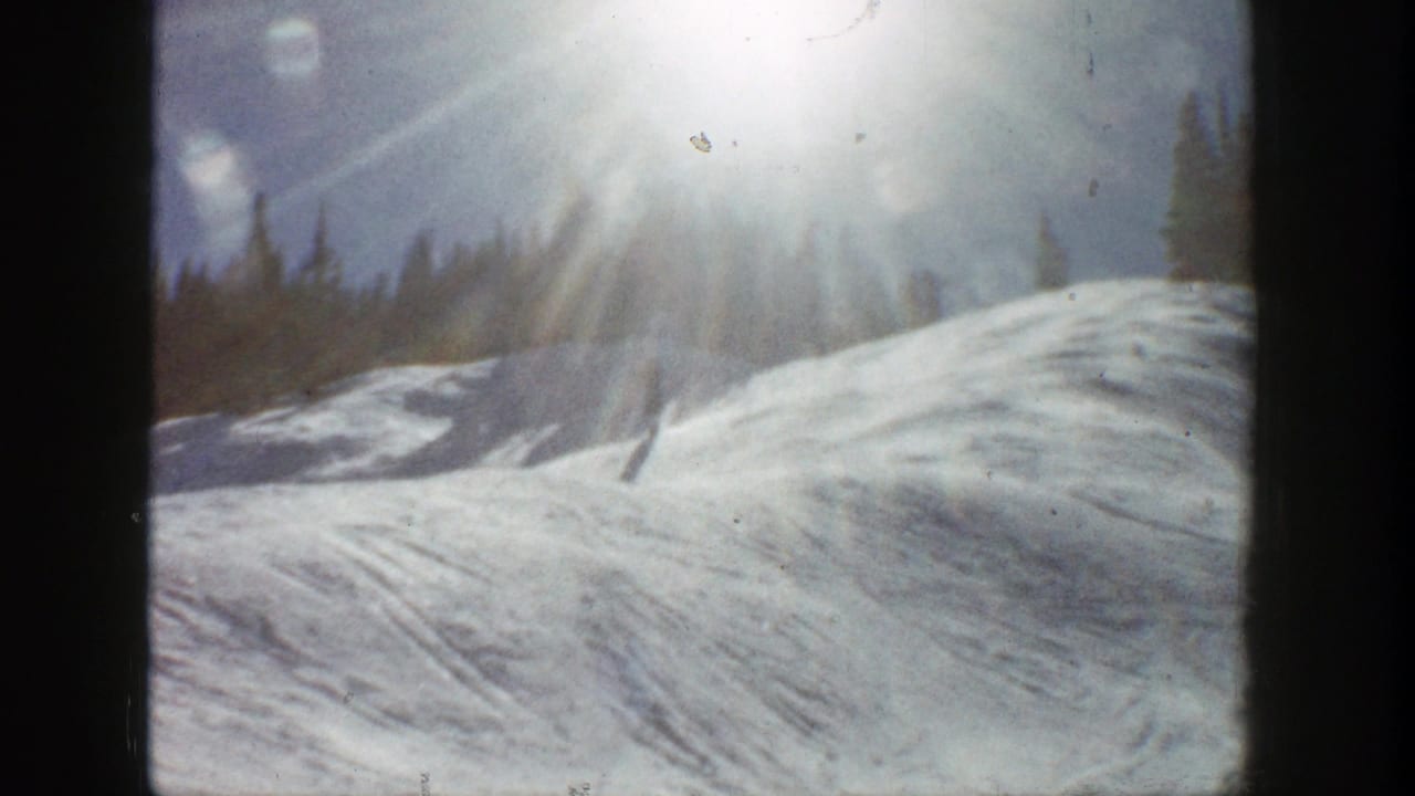 Snowy ridge and tree line seen through dark vertical frame edges.