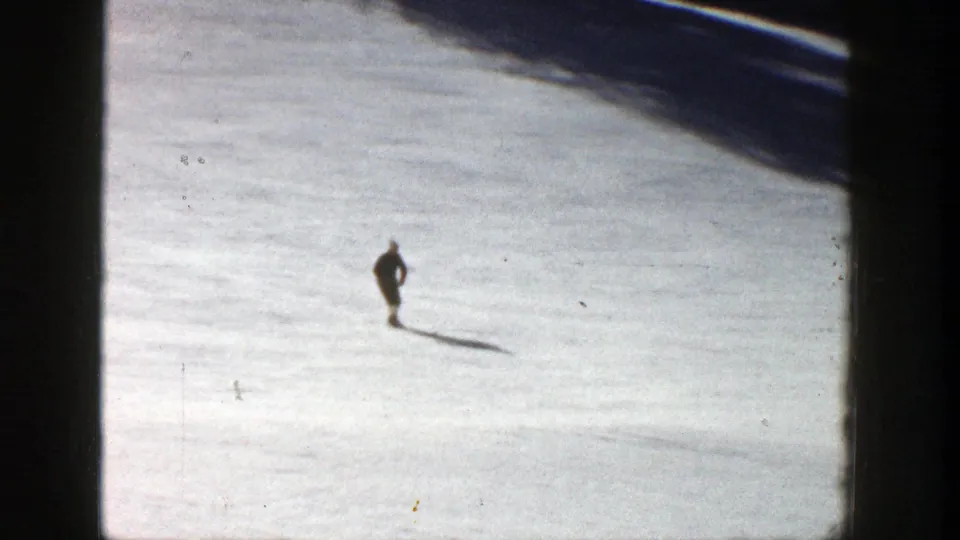 Distant skier on a sunlit Aspen snow slope in 1961, seen in soft 8mm color with film border visible.