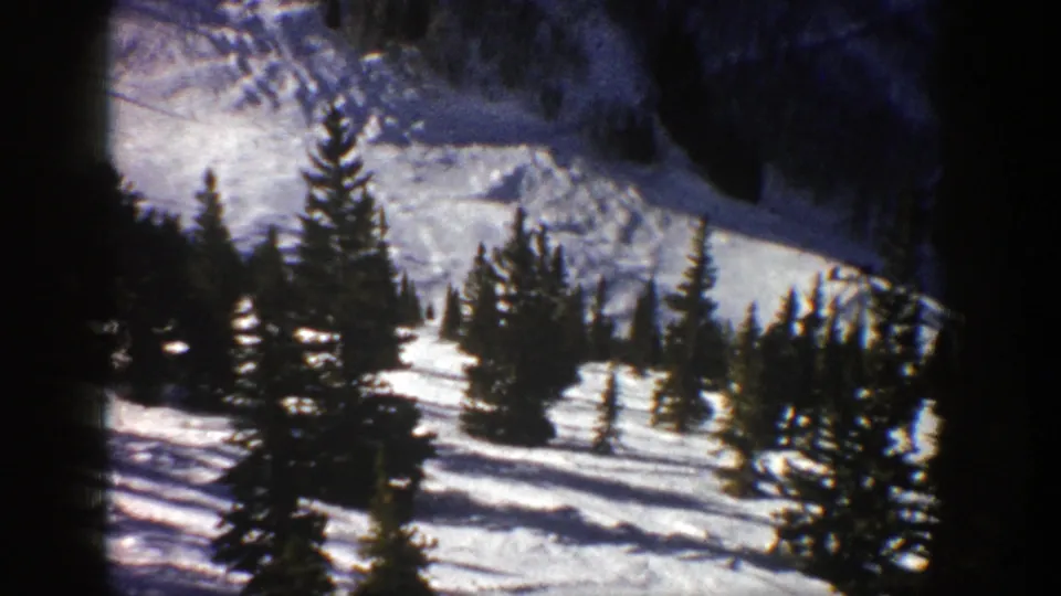 1961 Aspen winter landscape with dark evergreens crossing a bright, snow-covered hillside.