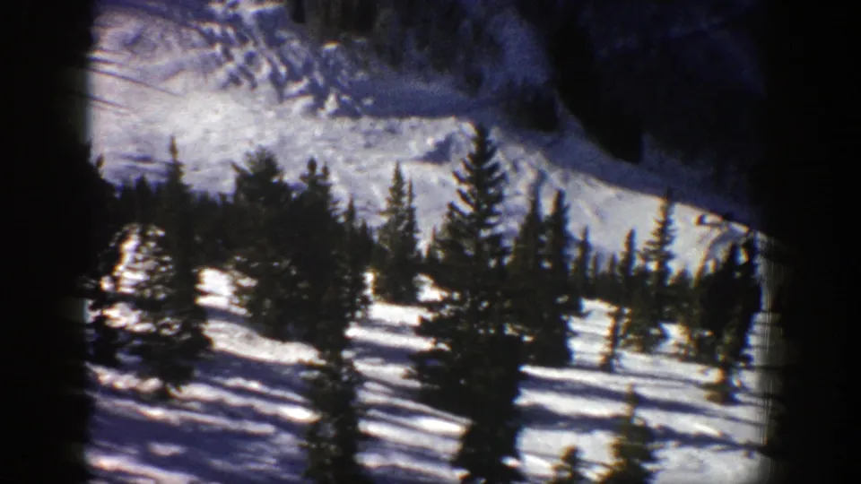 1961 Aspen landscape frame with evergreens in foreground and a snow-covered mountain slope behind them.