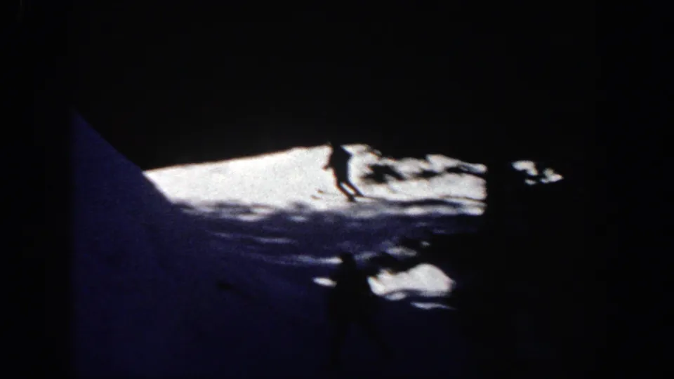 A distant skier appears in high contrast on a snowy Aspen slope, with deep foreground shadow and bright snow beyond.