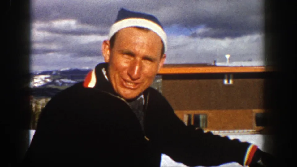 Adult man in a striped headband and dark jacket looks toward the camera during a snowy 1961 Aspen home-movie moment.