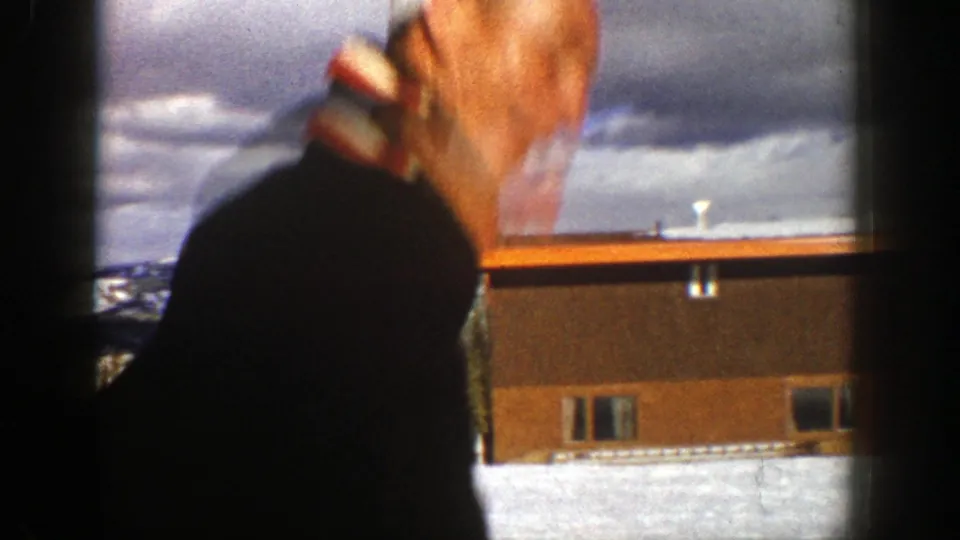 Adult man in a dark jacket appears to make a playful face as he turns beside a snowy building in Aspen, Colorado.