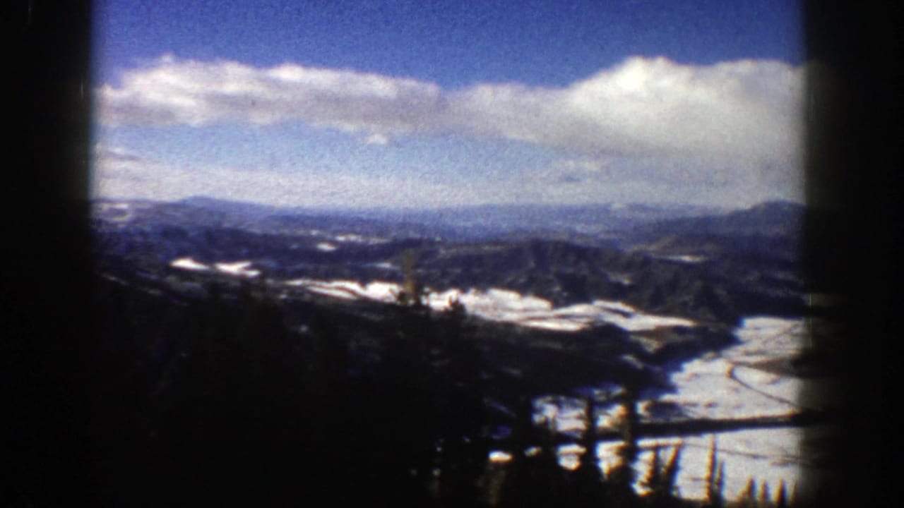 Snowy mountain valley seen from a ski lift with dark frame edges.