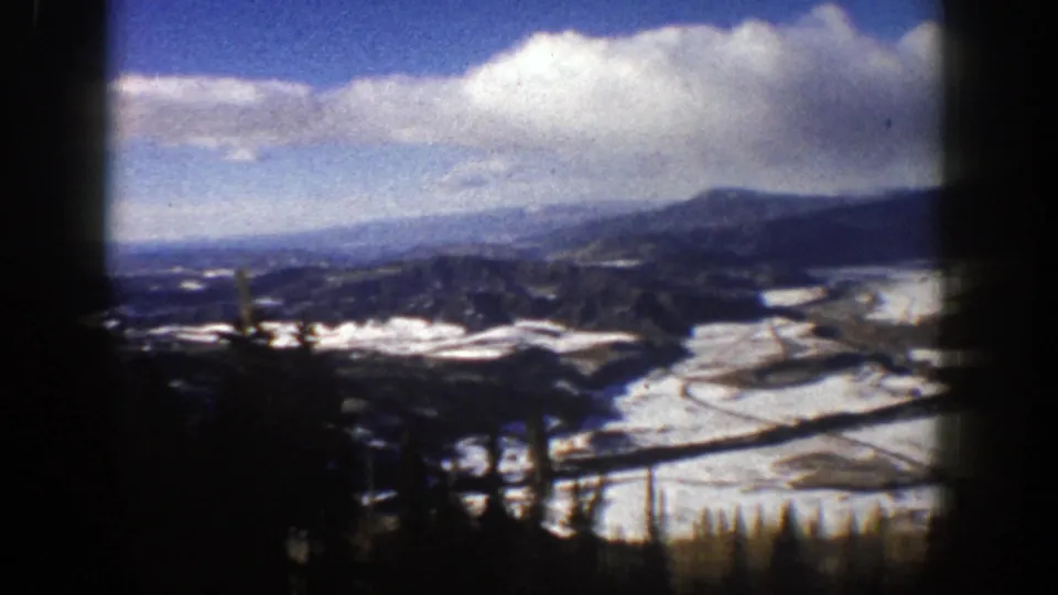The 8mm frame shows an Aspen-area winter panorama from the lift, with snow patches, dark trees, rolling hills, and distant ridges.