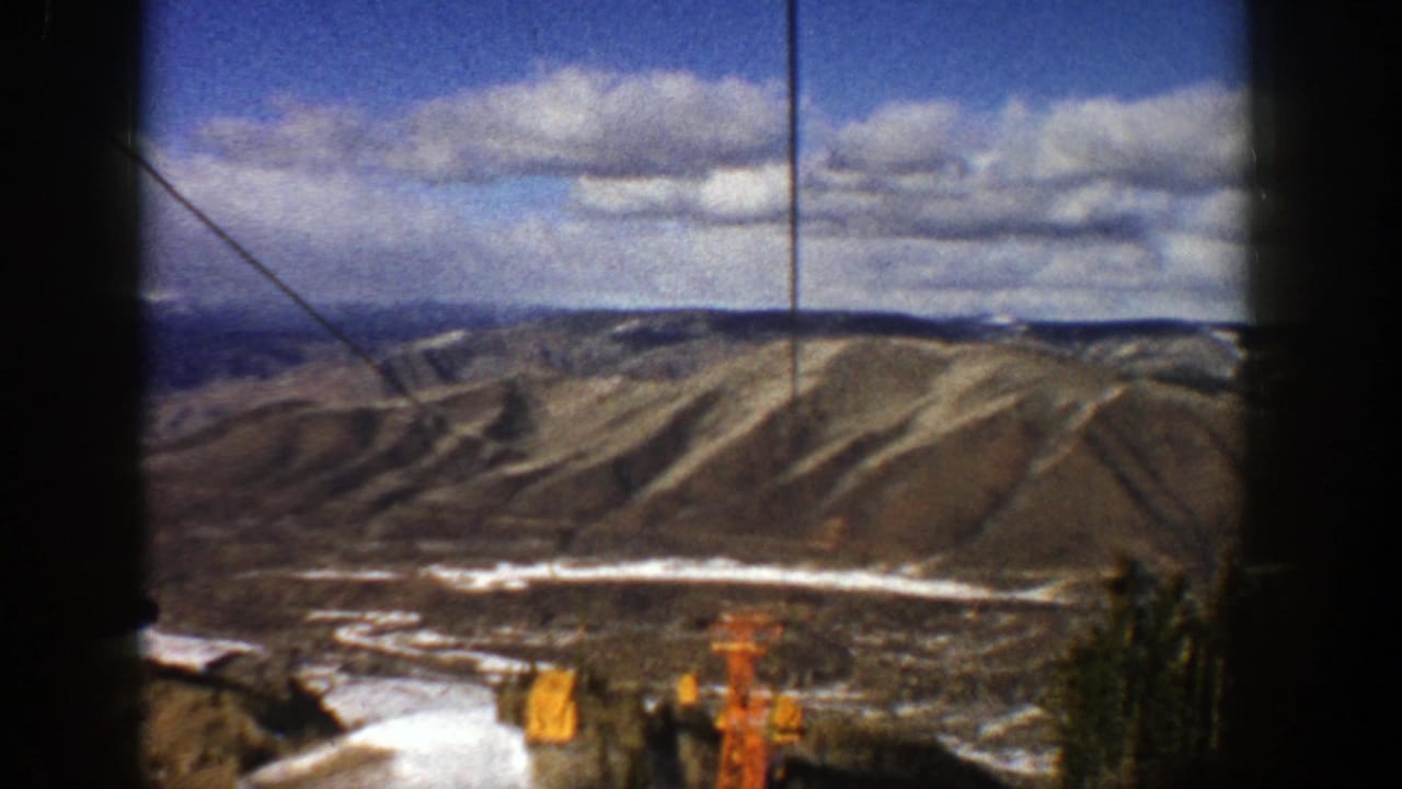 Aspen ski-area landscape in 1961, with rolling ridges, snow, lift cables, and orange lift equipment visible from above.