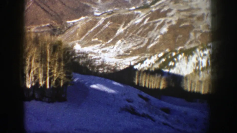 1961 Aspen frame with warm exposed mountain ridges, a dark tree band, and blue snow in the foreground.