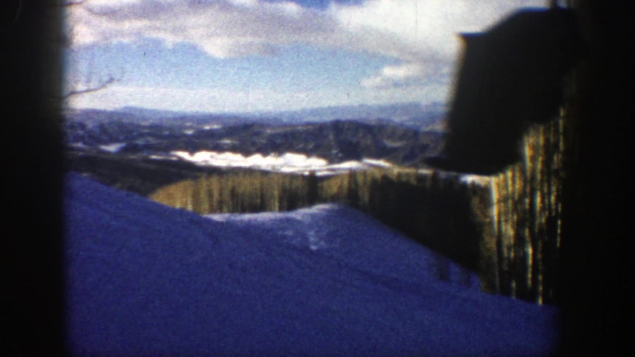 Snowy mountain slope with distant ridges and dark frame edges.