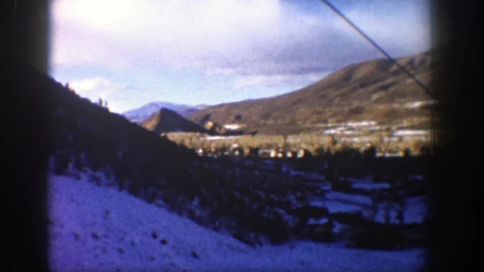 Elevated 1961 Aspen view across a snowy valley, distant mountains, and a small settlement below.