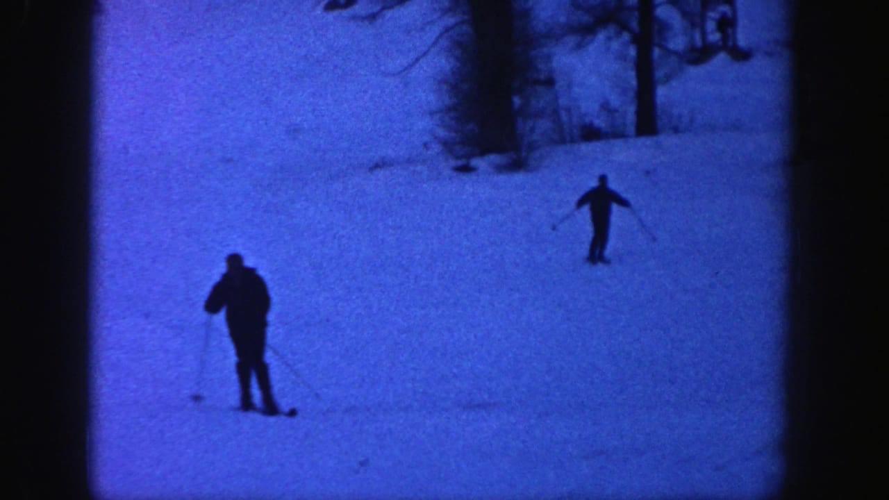 Two skiers move down a snow-covered Aspen slope in blue-tinted 1961 8mm home-movie footage.
