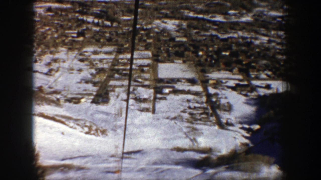 Aerial view of a snow-dusted valley with roads and scattered buildings.