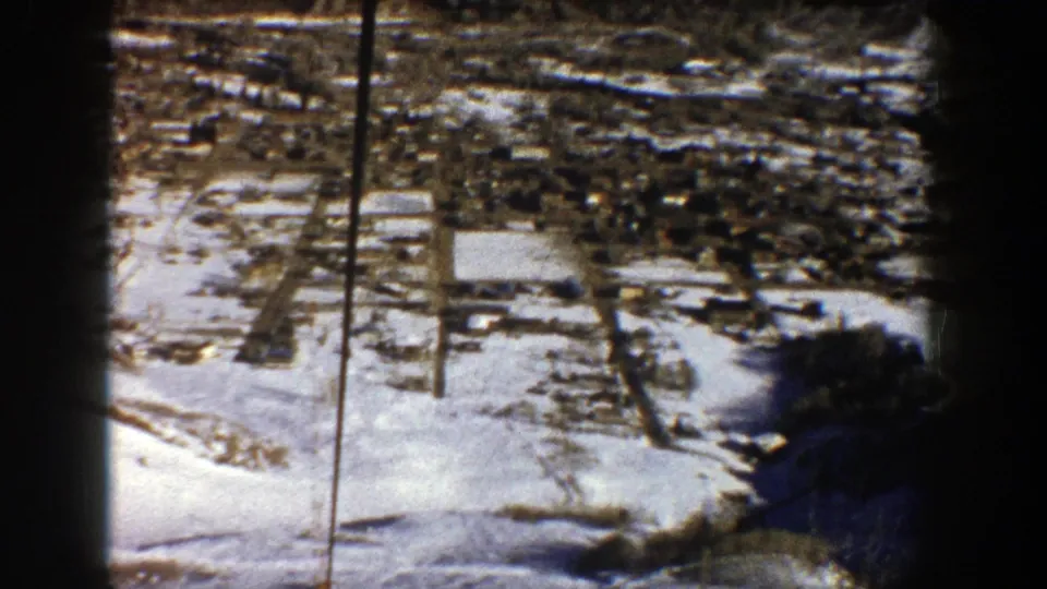 High-angle 1961 Aspen valley view showing snow cover, roads, clustered buildings, and aged 8mm borders.