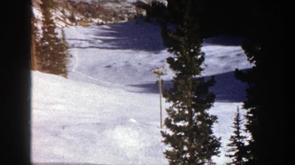 1961 Aspen ski slope view showing open snow, evergreen trees, faint tracks, and long winter shadows.