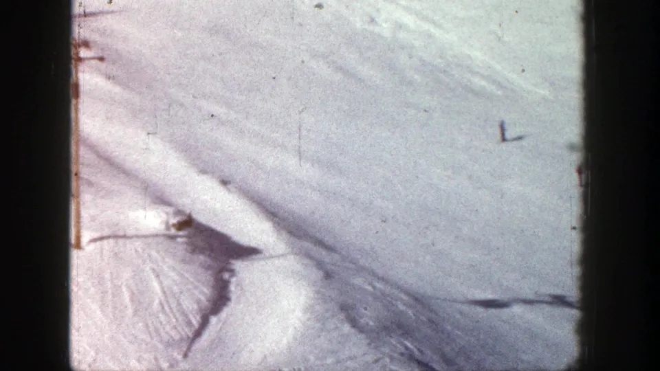1961 Aspen home-movie frame showing distant skiers on a bright snow-covered slope from above.