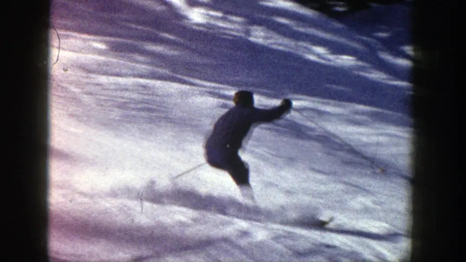 Distant skier on a snowy Aspen, Colorado slope, silhouetted in 1961 8mm home-movie footage.